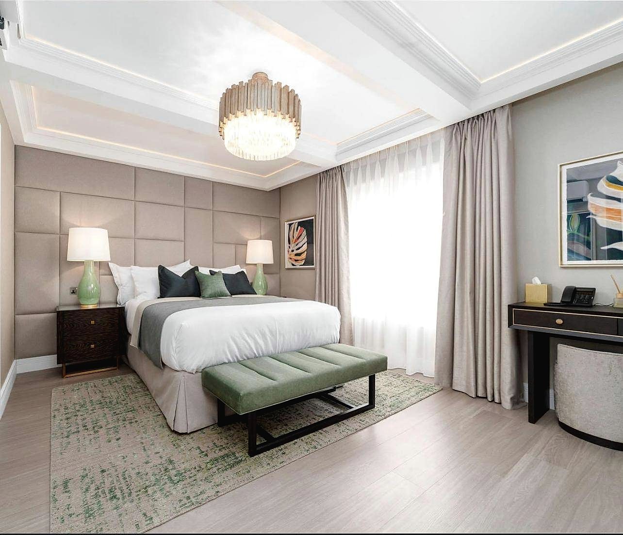 Bedroom with panelled headboard wall and green bench