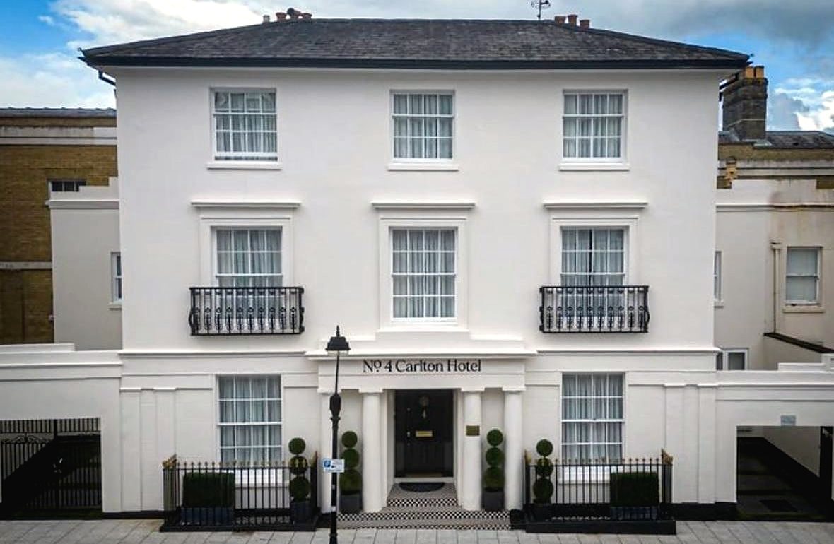 Restored front elevation of a white rendered listed townhouse hotel with black railings