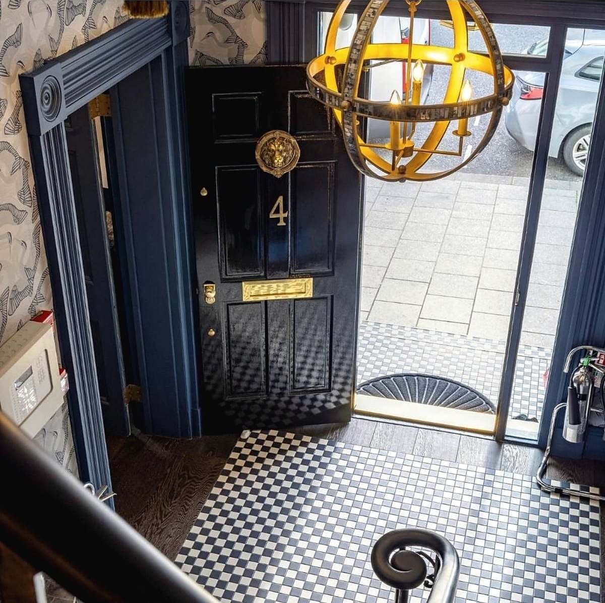 Restored panelled front door in gloss black with brass furniture, viewed from the stair