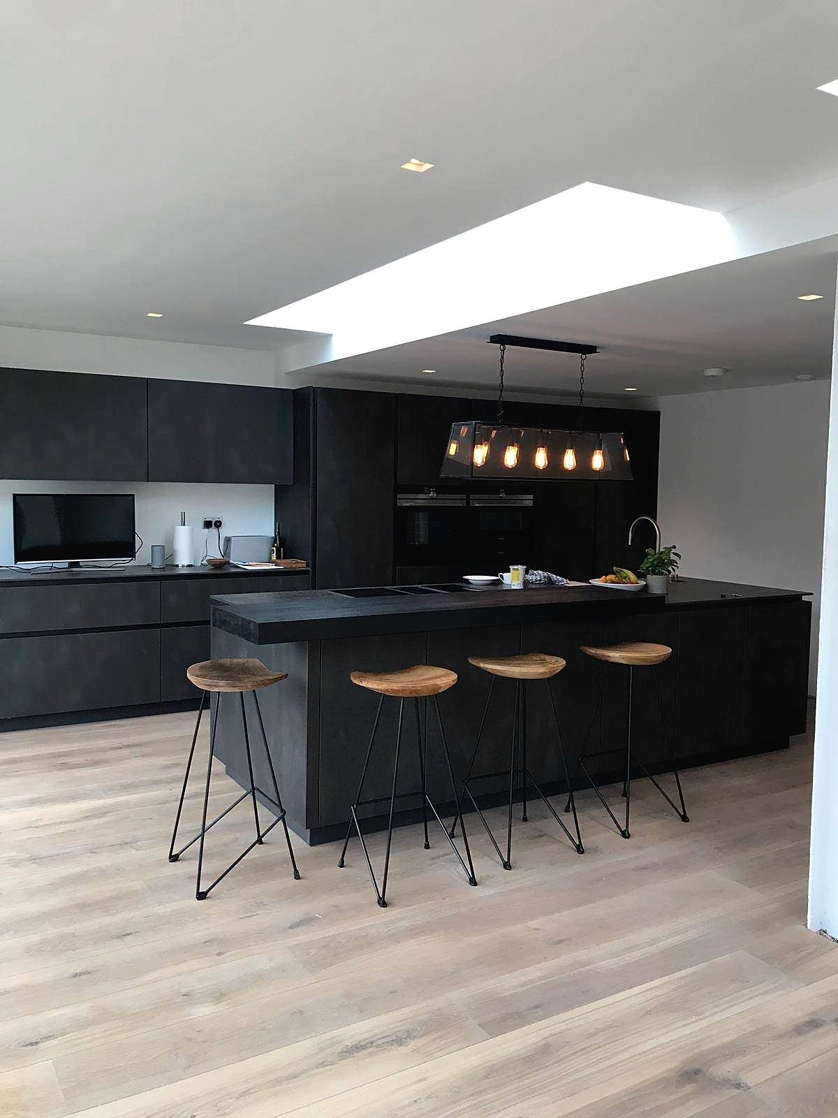 Open plan kitchen with dark handleless units, island and oak flooring