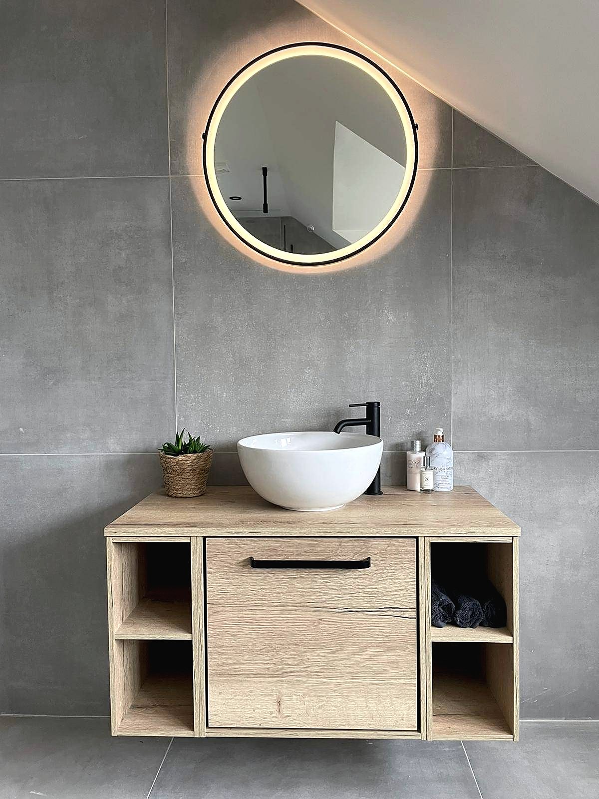 Loft bathroom with large format grey tiles, oak vanity and round lit mirror