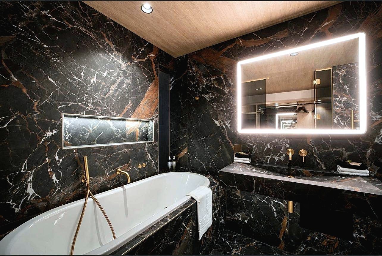 En suite in dark veined stone with brass fittings