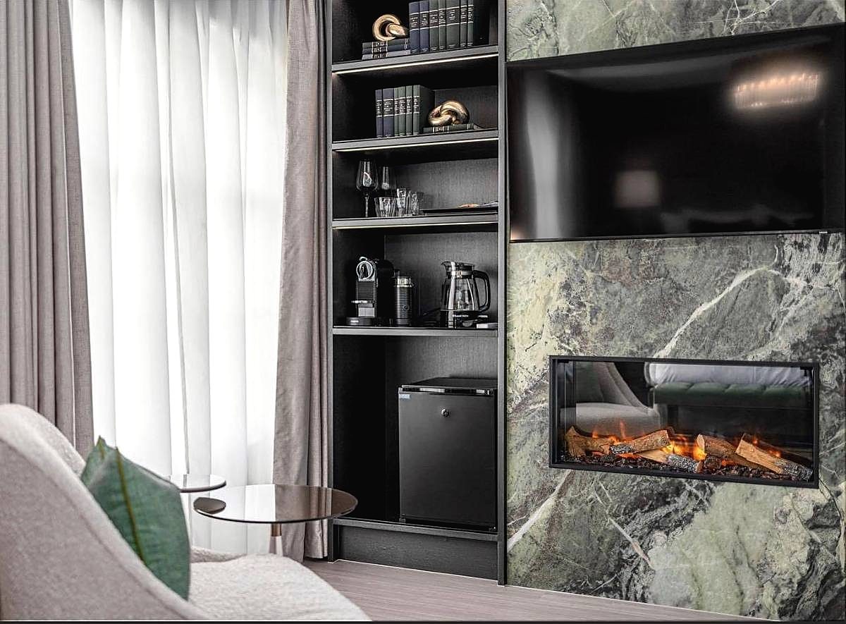 Living room media wall in book matched marble with a recessed fire and dark joinery, completed by JSV