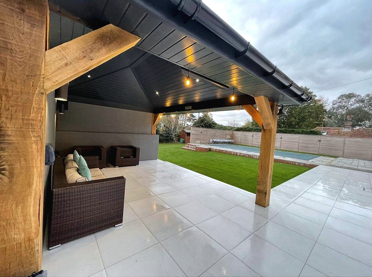Oak framed garden structure with dark boarded ceiling looking out to a pool