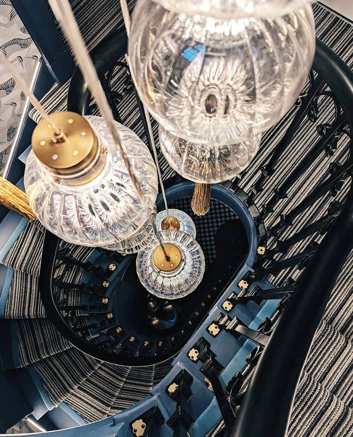 Looking down a spiral staircase through a cascade of ribbed glass pendants